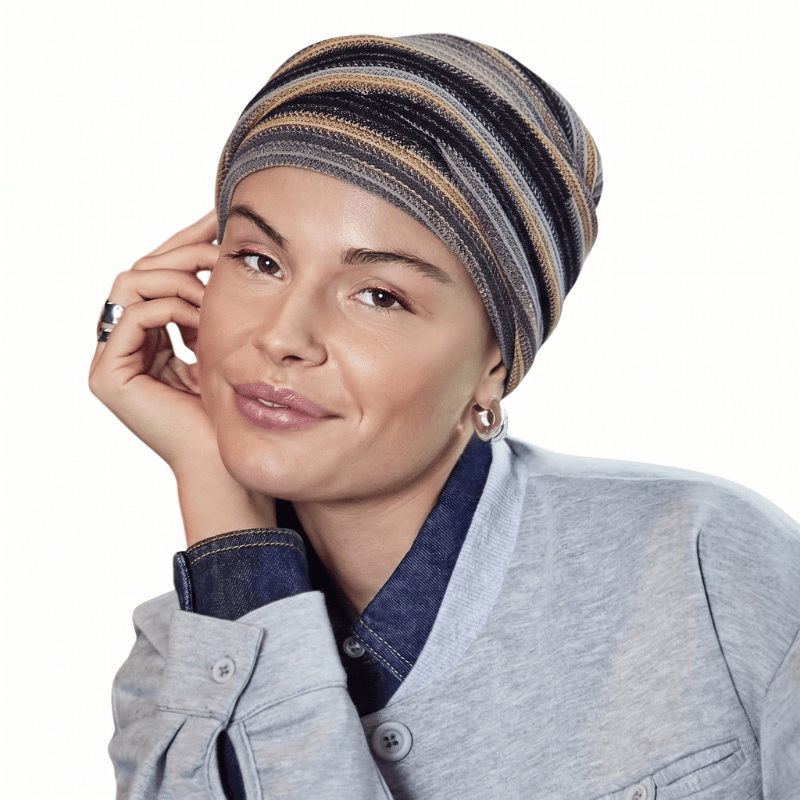 Hymyilevä nainen yllään Zoya-turbaani Black Autumn Stripes -kuviolla ja pehmeillä laskoksilla, edestä